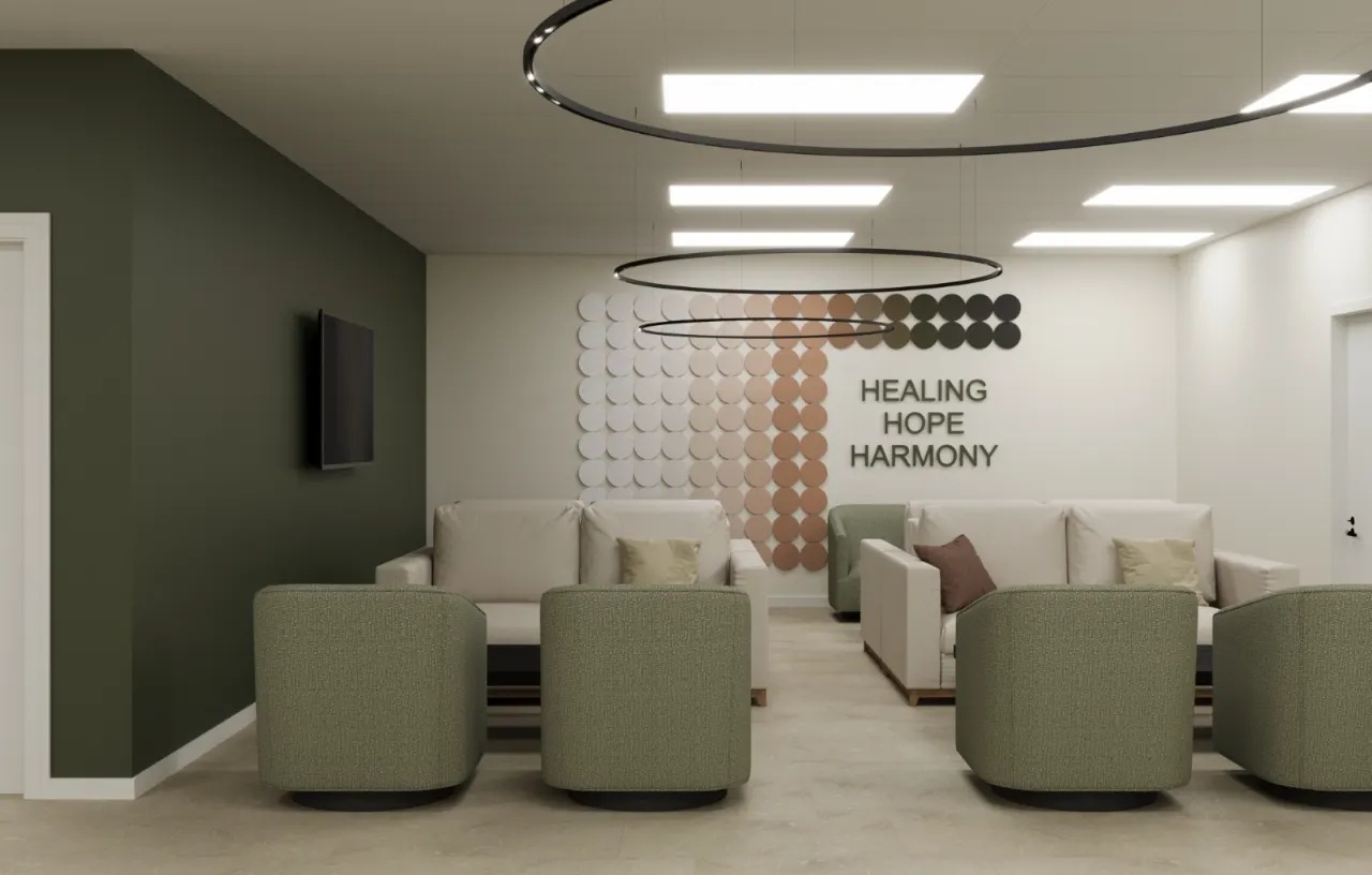 Addiction treatment center group lounge in Indianapolis with sage green lounge chairs, a “Healing, Hope, Harmony” feature wall and circular pendant lighting